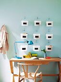 Creative storage system - small plastic buckets hanging on wall hooks above simple desk and 50s armchair