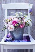 Bouquet of roses with pink yarrow and chamomile in zinc bucket
