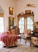 Romantische, antike Sofaecke mit floralen Polstermöbeln und Vintagekommode vor orientalisch verblendetem Sprossenfenster