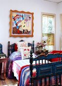 Antique, blue country bed with colorful bed linen under a modern, Pop Art painting