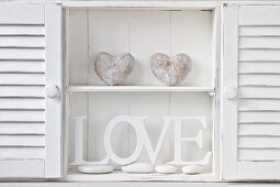 Cabinet holding white-painted wooden letters and stone heart sculptures