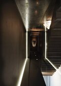 Minimalistischer Gang mit Beleuchtung und Blick durch Glastrennscheibe auf Treppe