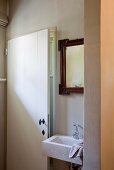 Small stone sink and antique, framed mirror next to white, country-house door