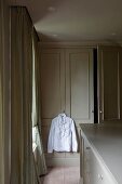 Ankleidezimmer - Weisses Hemd auf Kleiderbügel an Griff einer Schranktür aufgehängt