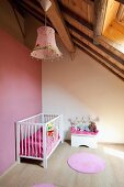 Cot in minimalist nursery in renovated attic with exposed wooden roof structure