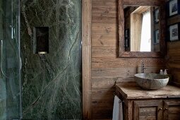 Steinwand mit Wandnische im Duschbereich eines rustikalen Badezimmers mit Steinwaschschüssel und Holzwaschtisch