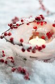 Ice tealight holder with winterberries and candle in artificial snow