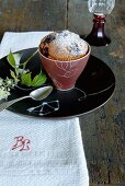 A ceramic cup with miniature Christmas cake on a white monogrammed cloth