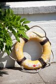 Old life belt leaning against white brick wall