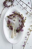 Wreath of callicarpa berries and silver spoon with name tag on white dish