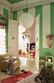 Child's bedroom with green and white striped walls and double doors leading to playroom