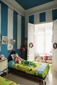 Blue walls with white stripes in child's bedroom with twin beds