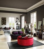 Ottoman with red velvet upholstery, sofa set and tall windows in elegant salon