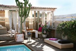 Sommerstimmung auf Terrasse - Pool und Pflanzenkübel vor überdachten Terrassenmöbeln