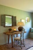 Rokoko Stuhl und rustikaler Holztisch vor Spiegel mit Holzläden an grün getönter Wand