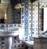 Tradionelles Badezimmer mit Standwaschbecken vor weiss blau gefliester Wand und Spiegelleuchte mit weißem Schirm