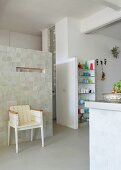 Loft-style interior - white-painted, vintage wooden chair against partition installation and masonry shelving in open-plan kitchen