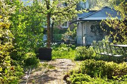 Frühlingstag - Terrassenplatz vor Gartenhäuschen aus Holz in blühendem Garten