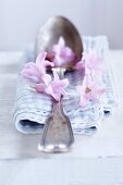 Vintage Löffel aund abgezupften Blüten einer rosa Hyazinthe auf blau karierter Serviette