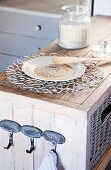 A plate with grains of rice and a decorative metal trivet on a rustic shelf unit with metal wall hooks