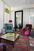 Hotel Loungebereich - Glastisch und farbige Sessel auf gemustertem Teppich im Vorraum mit weisser Holzverkleidung