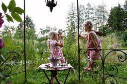 Two blonde girls with cherries in garden pavilion