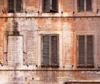 Weathered building facade with wooden shutters (Italy)