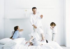 Girl and boys having pillow fight with man