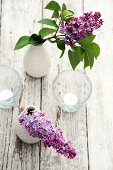 Purple lilac in vases and tea lights on wooden table