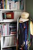 Ties and hats on clothes rack in front of bookcase