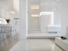Offener, minimalistischer Wohnraum mit Essplatz und Blick in Vorraum mit Treppenaufgang in Weiß