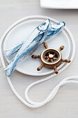 Chocolate fish and miniature ship's wheel on plate with cord