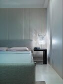 Modern bedroom with double bed next to bedside table with lamp