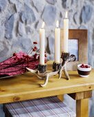 Artificial antler candelabra on wooden table top in front of stone-effect panel