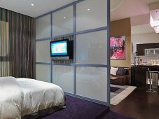 Offener Schlafbereich mit Raumteiler aus Glas und Fernseher