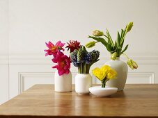 Verschiedene Frühlingsblumen in Vasen auf Holztisch