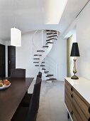 Modern dining area and sideboard in a contemporary living room with spiral staircase