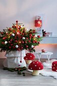Decorated Christmas tree and decorative mushrooms on floor next to white table in front of stacked presents on wall console