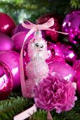 Pink Christmas tree baubles and dog figurine on fir branch