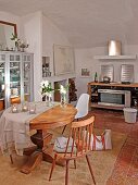 Runder Holztisch mit schlichtem Küchenstuhl und Bauhaus Schalenstuhl in mediterranem Esszimmer mit kleinem Kochbereich