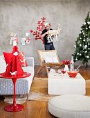 Christmas atmosphere - Christmas decorations on red side table in front of designer sofa and coffee table and man holding reindeer ornament next to Christmas tree