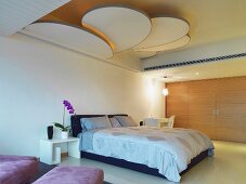 Fächerartiges Deckenpaneel in einem modernen Schlafzimmer mit Einbauschrankwand