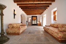 Florale Sofas im Eingangsbereich einer spanischen Villa mit Steinfussboden und Holzbalkendecke
