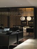 Elegante Ledersesselgarnitur vor transparentem Raumteiler aus Metall und Blick in Lounge
