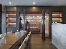 Moderner Esstisch aus hellem Holz und Blick durch offene Tür in Designer Wohnraum
