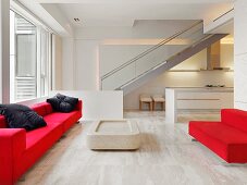 Rote Sitzmöbel auf hellem Steinboden in offenem Wohnraum mit Treppe