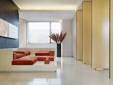 Sofa-Objekt mit Polstern auf Podest vor Wand aus drehbaren Raumteilern