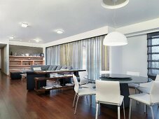 Sofalandschaft und runder Esstisch im modernen, offenen Wohnraum mit Edelholzparkett