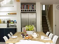 Set breakfast table in open-plan kitchen with stainless steel side-by-side fridge and view of staircase
