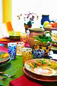 Colourful dining table with brightly painted ceramic crockery and patterned glasses